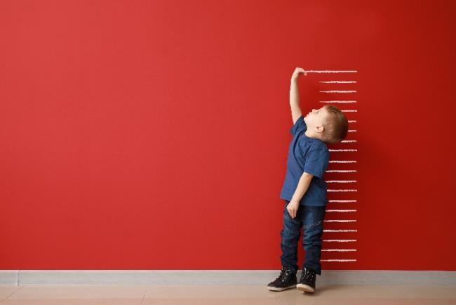 ילד קטן מודד גובה על גבי הקיר 