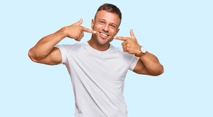 גבר צעיר עם חיוך לבן וצחור אחרי הלבנת שיניים