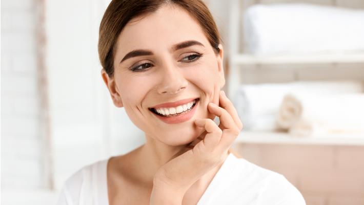 אישה מחייכת חיוך אסתטי אחרי השתלת שיניים ממוחשבת
