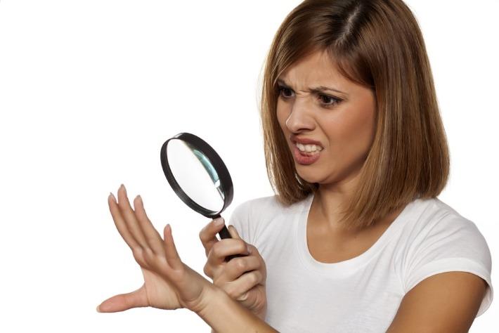 אישה צעירה בוחנת את הציפורניים שלה בדאגה ומבחינה בסימנים שיכולים להעיד על מחלות שונות