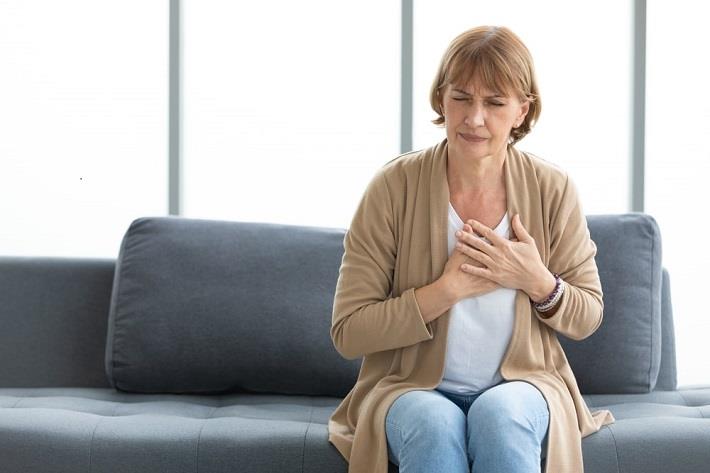 אישה אחרי גיל המנפאוזה תופסת את החזה, סובלת מאי ספיקת לב