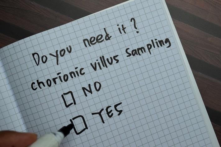 מחברת שבה כיתוב באנגלית "האם את צריכה לבצע בדיקת סיסי שליה, בדיקת CVS, וסימון של כן ולא