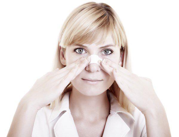 אישה אוחזת בסד שעל אפה לאחר שעברה ניתוח אף